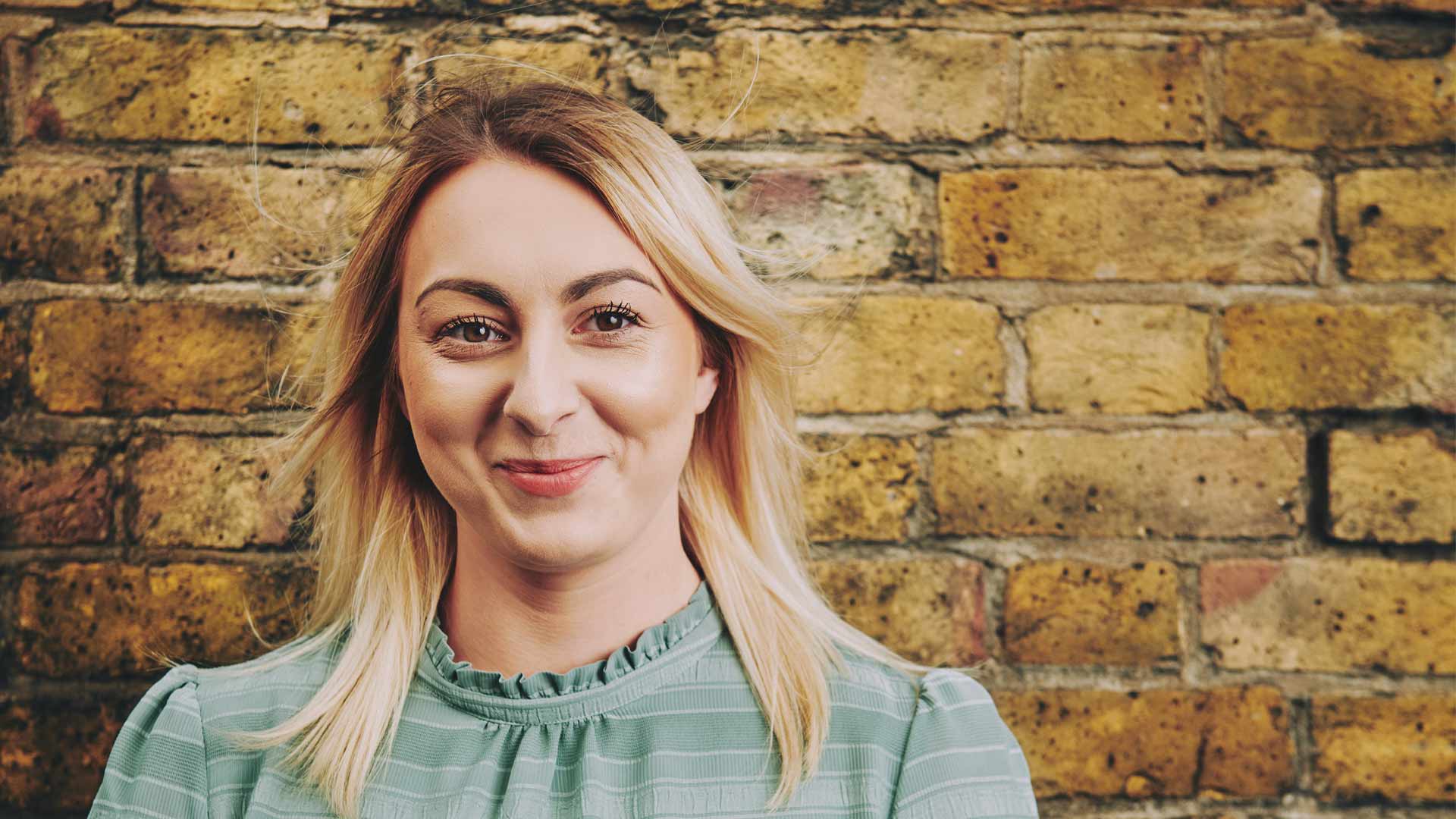 woman standing in front of a wall smiling