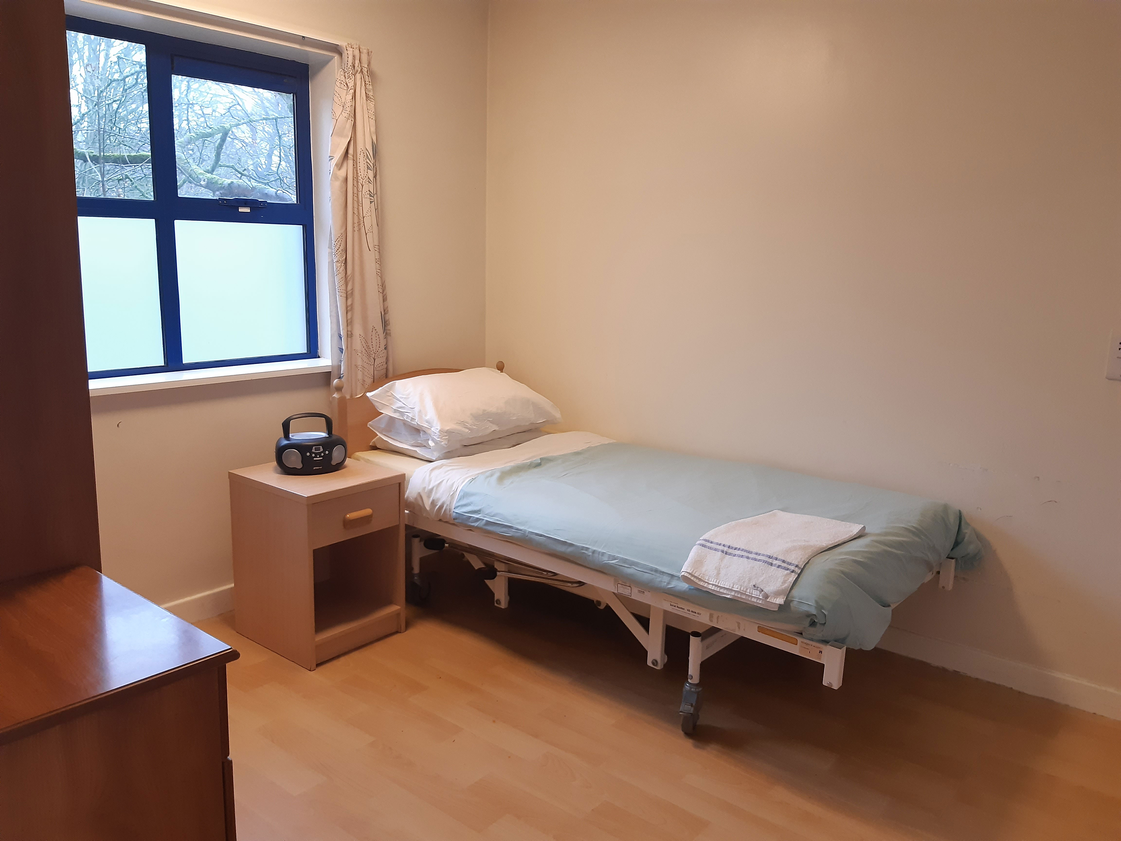 Bedroom - a single bed with blue sheets, a window and plain white walls