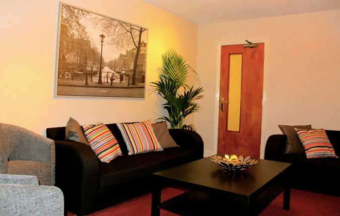 A lounge with two sofas, a coffee table, and art on the wall