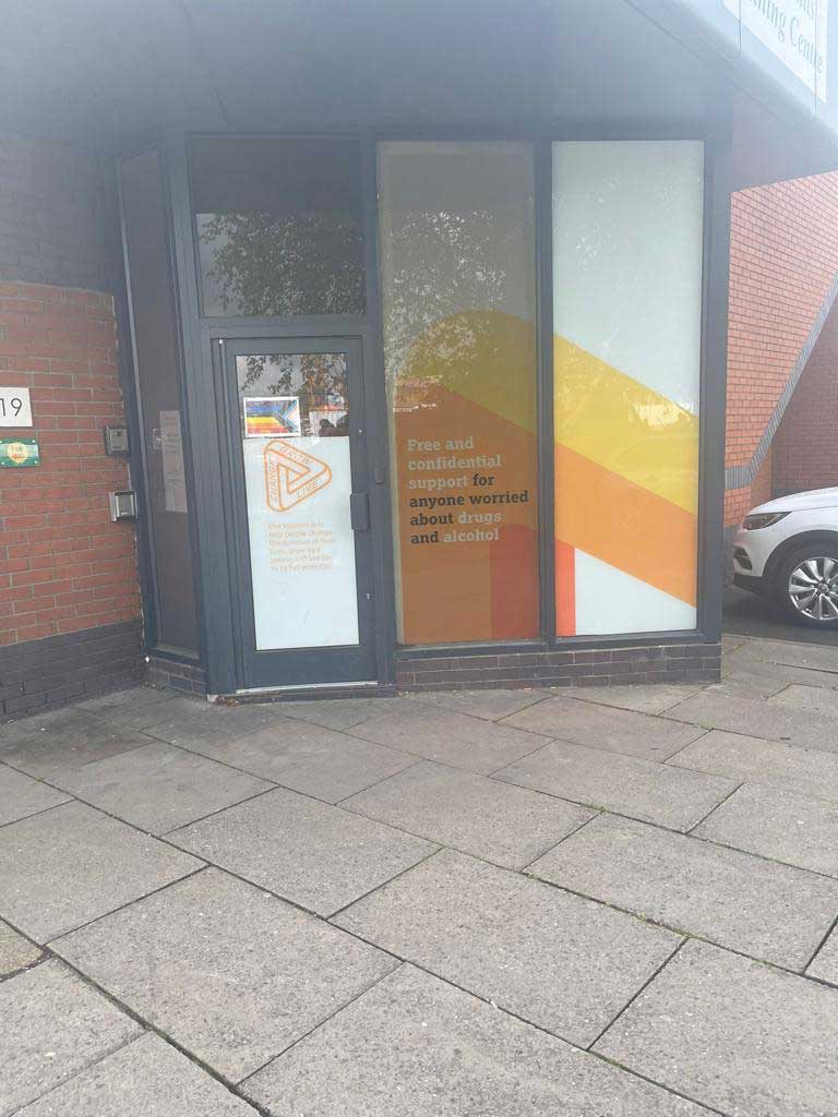Outside of the Crew Building - The street entrance, including floor to ceiling windows with orange decals in them.