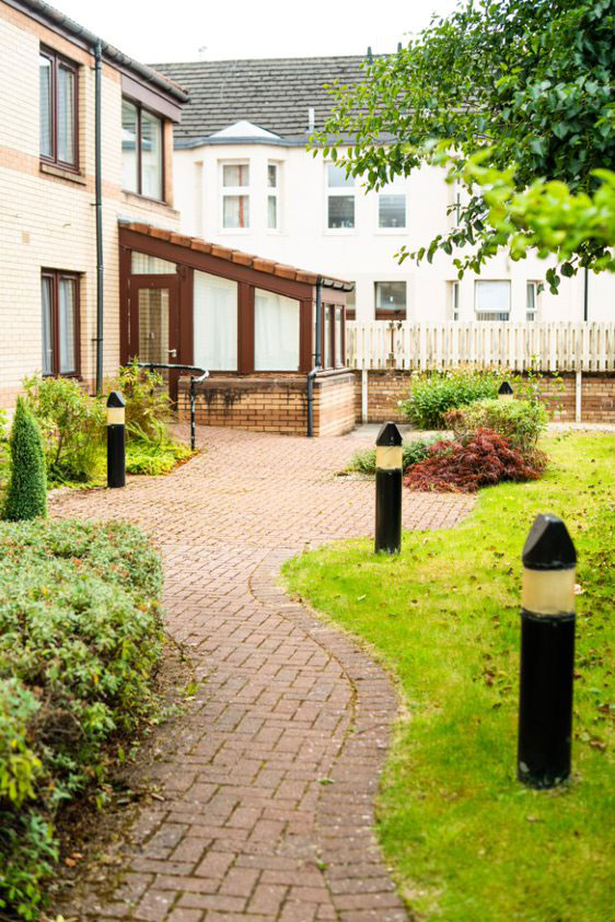 The garden at Phoenix Futures - the building is in the background, there is a wiggly path in the foreground lined with grass and solar lamps