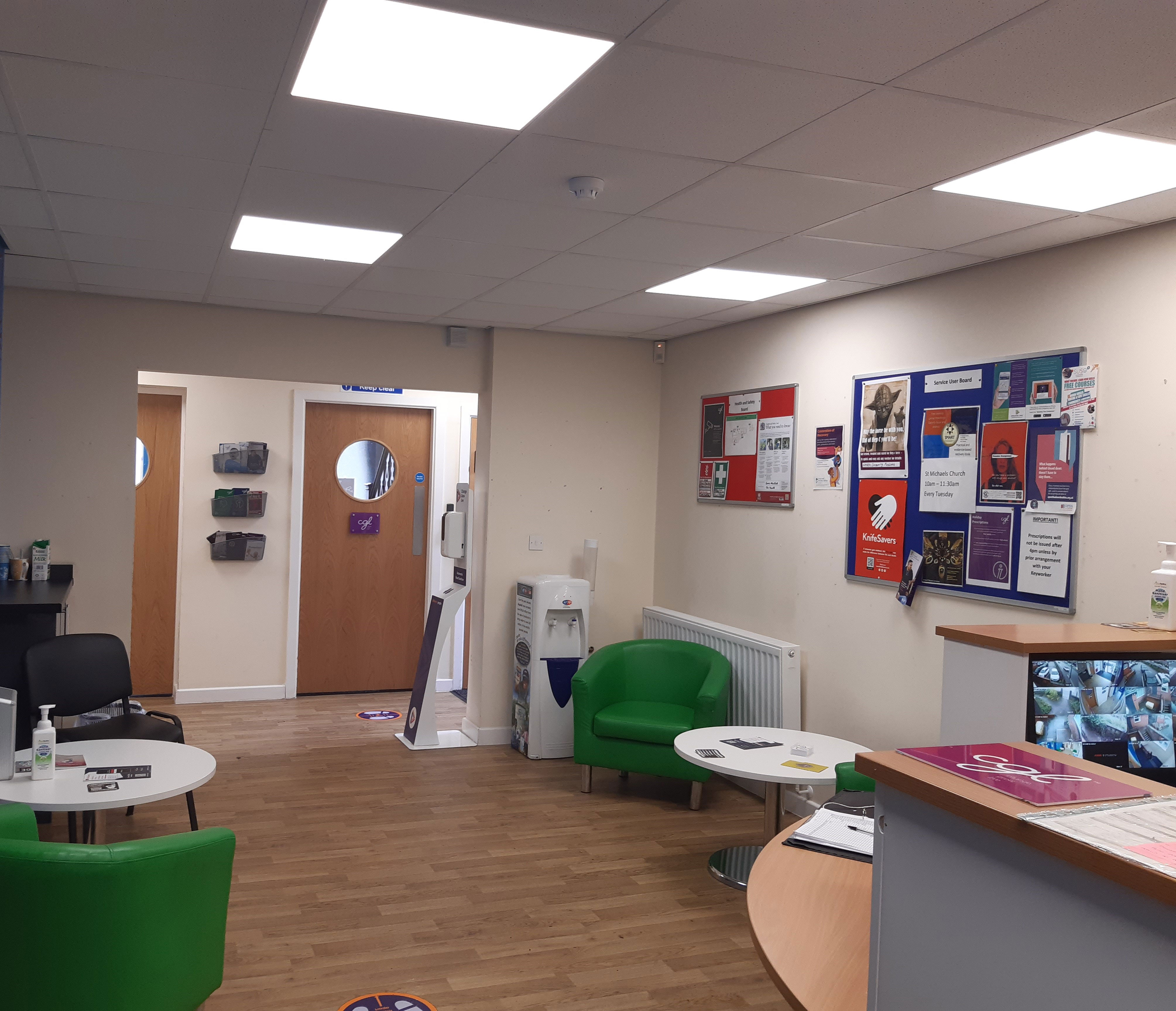 The Macclesfield Reception Area - a room with white walls, green seating and a display board