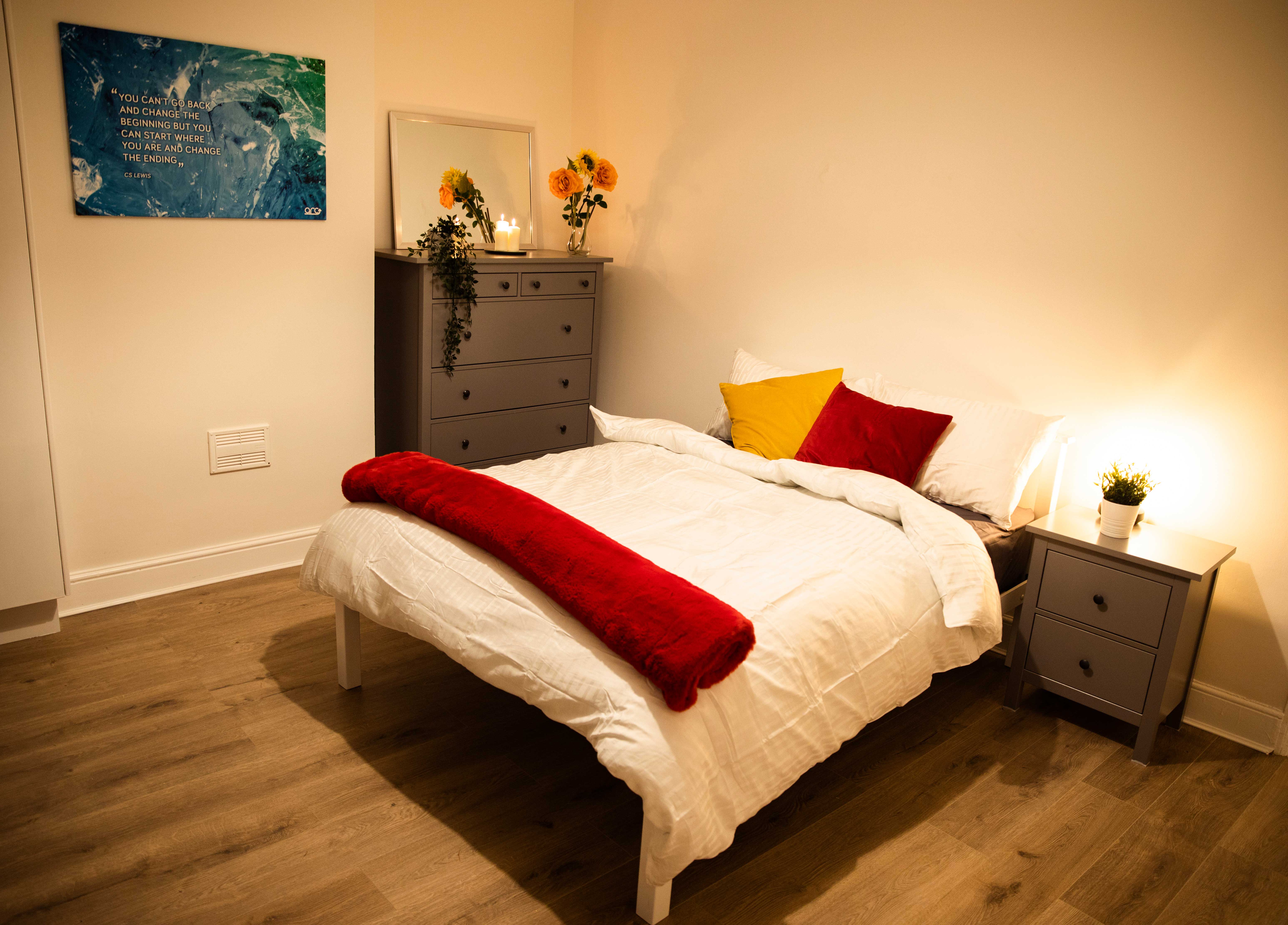 bedroom with a double bed in the centre of the room. There is a bedside table and a chest of drawers next to the bed.