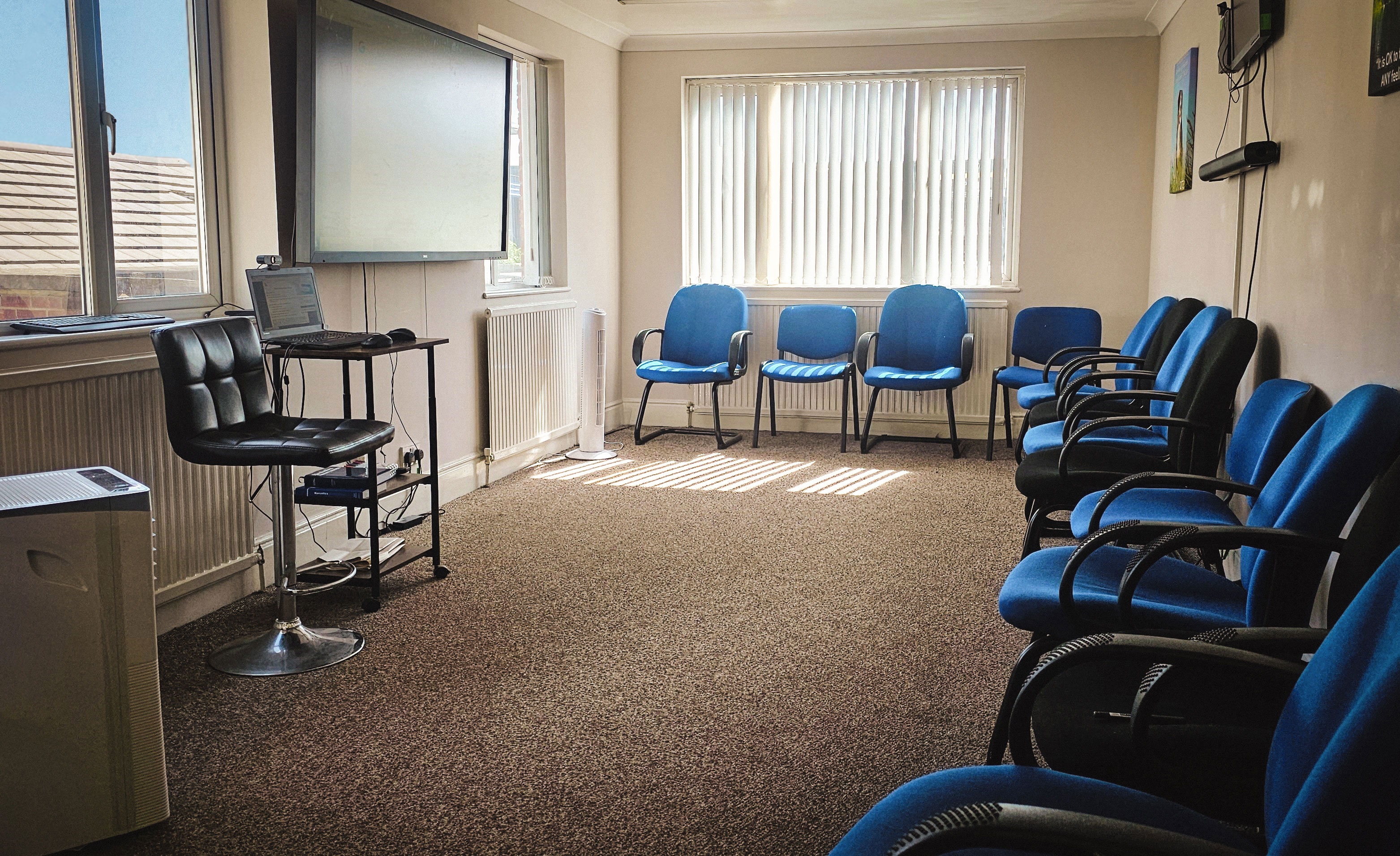 A room with chairs around the edge facing a TV mounted to the wall.