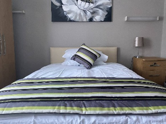 A single bed with a wardrobe and a bedside table on either side.