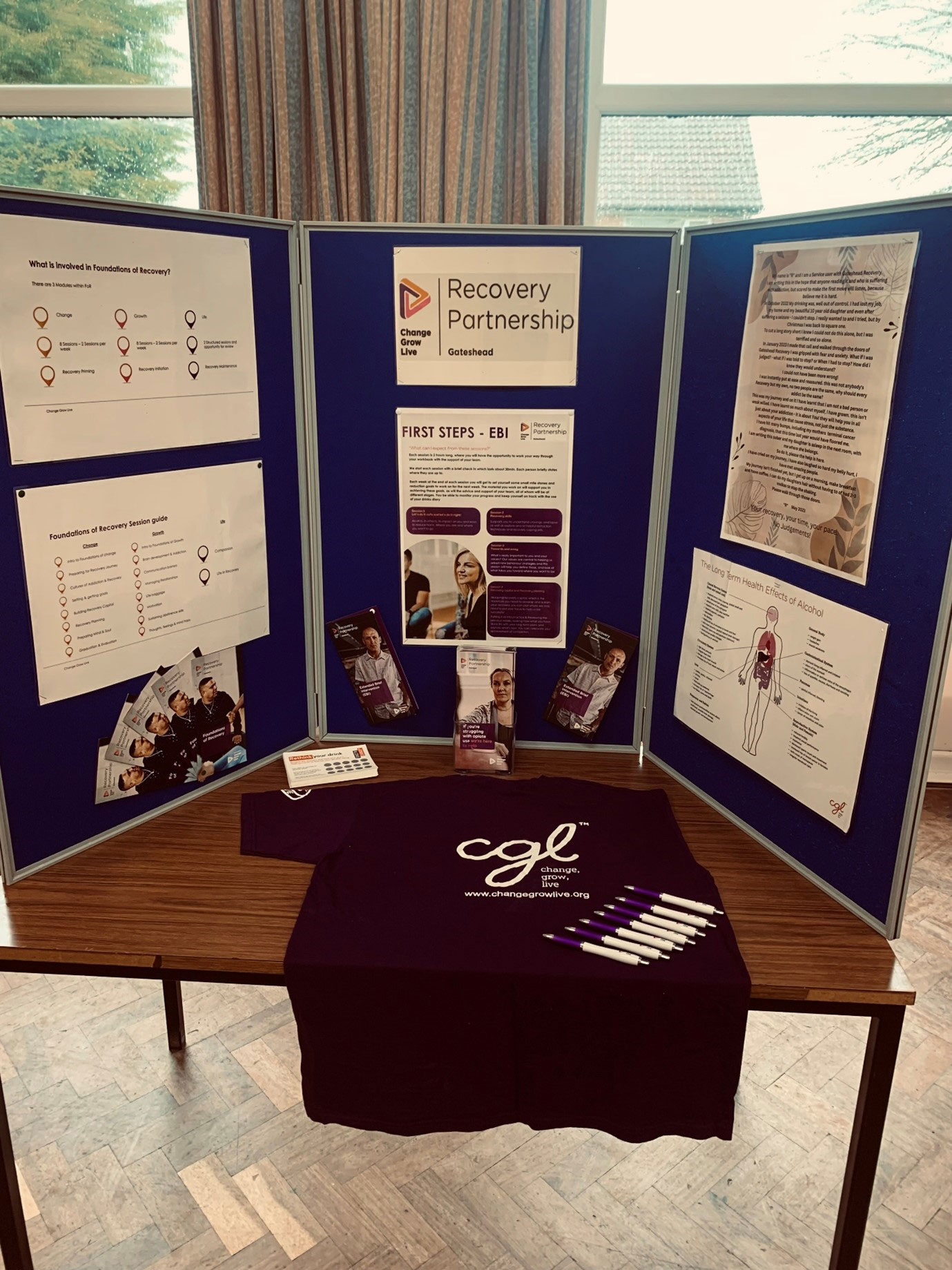 A close up of the stall, with poster boards around the edge and a t-shirt on the table