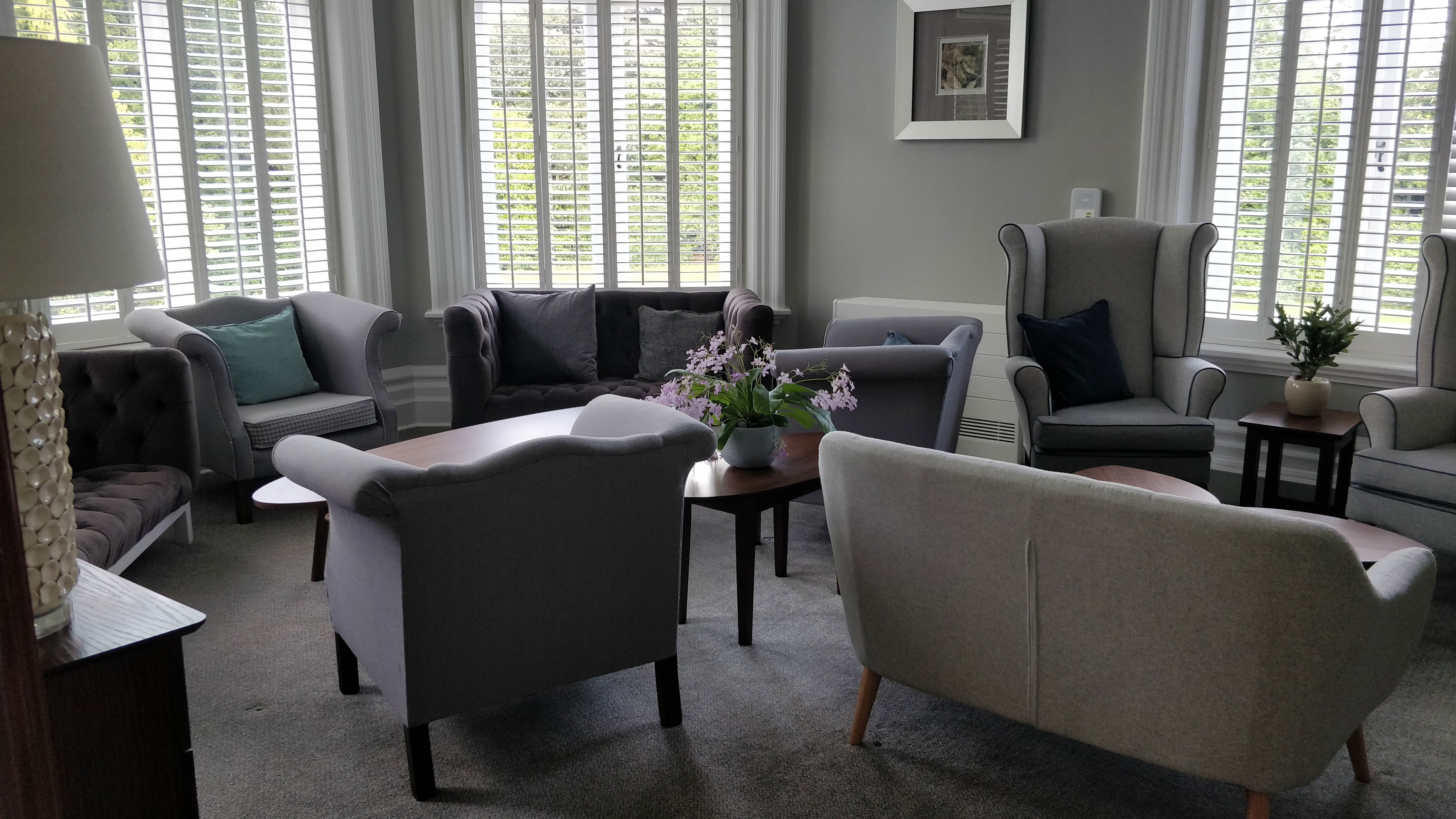 A living room with plush chairs and sofas, with big windows.