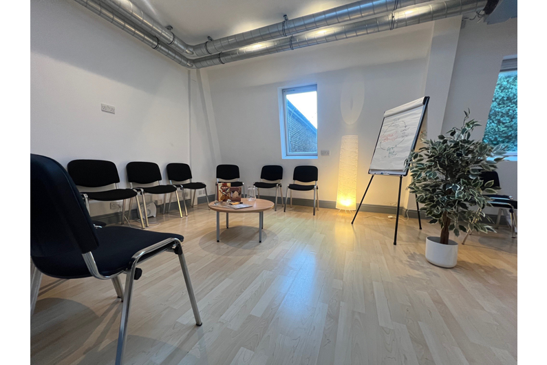 An open airy room with chairs around the edge and a flipchart in the corner