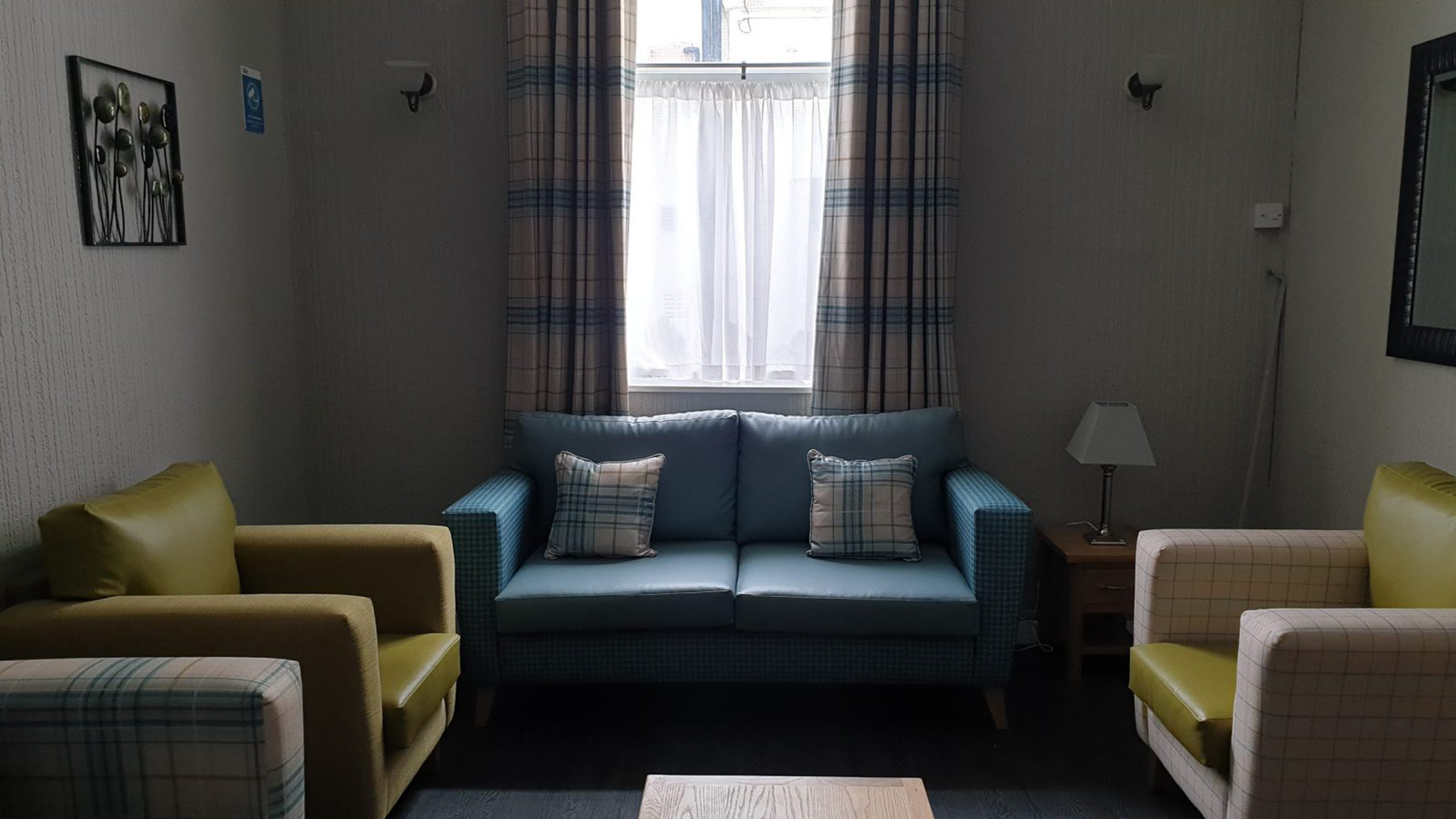 A sofa and arm chairs arranged around the edge of a room with a coffee table in the middle
