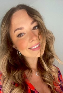 A young woman taking a selfie, she has light brown curled hair