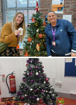 A man and a woman stood in front of a christmas tree smiling at the camera