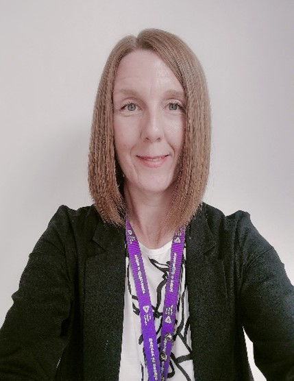 A woman taking a selfie wearing a black blazer. She has a shoulder length bob haircut