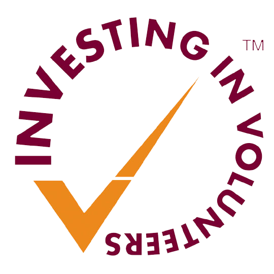 The Investing in Volunteers logo, an orange tick in the middle of the circle with the words 'investing in volunteers' curving around it in purple