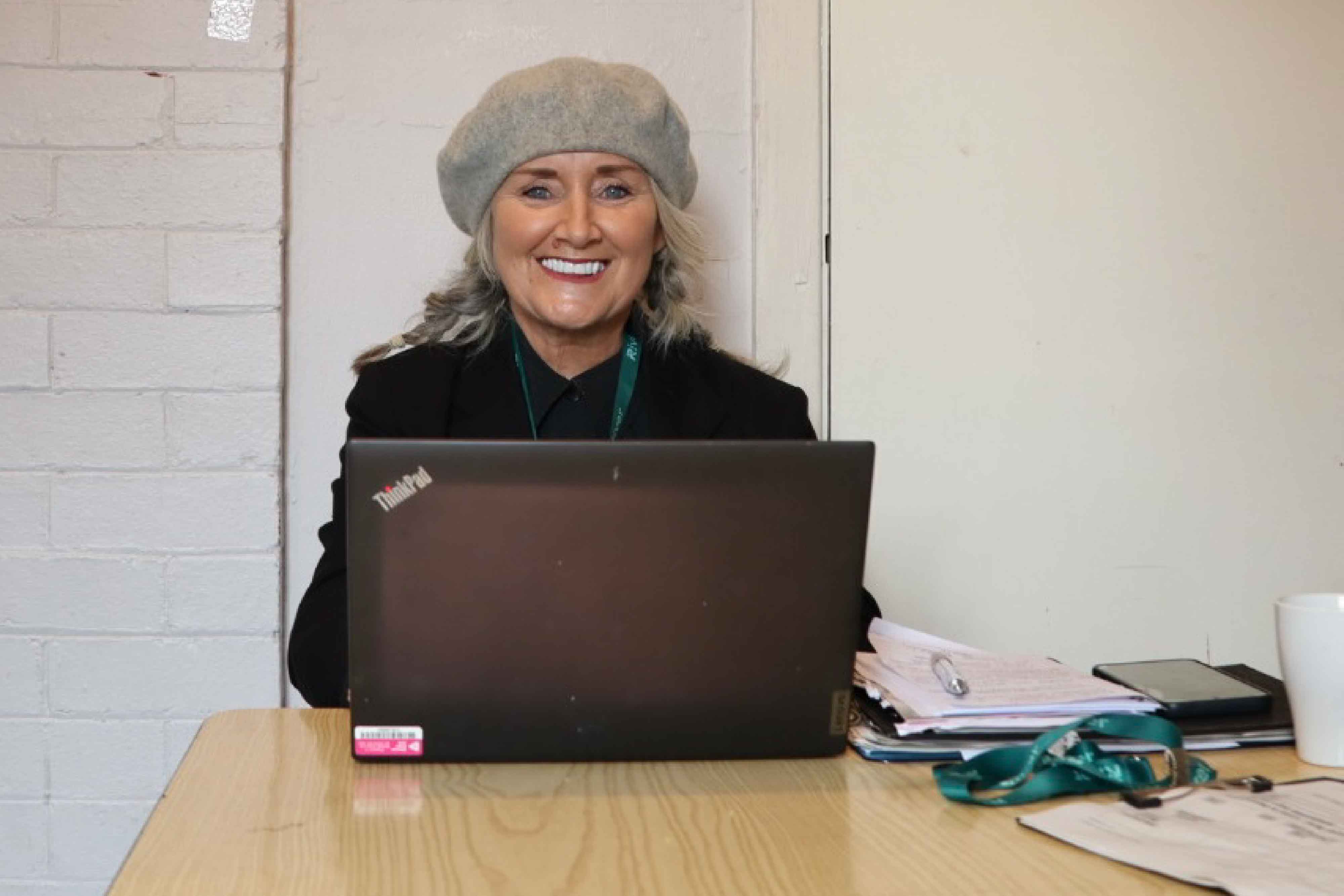 Service manager Julie smiling at camera with her laptop