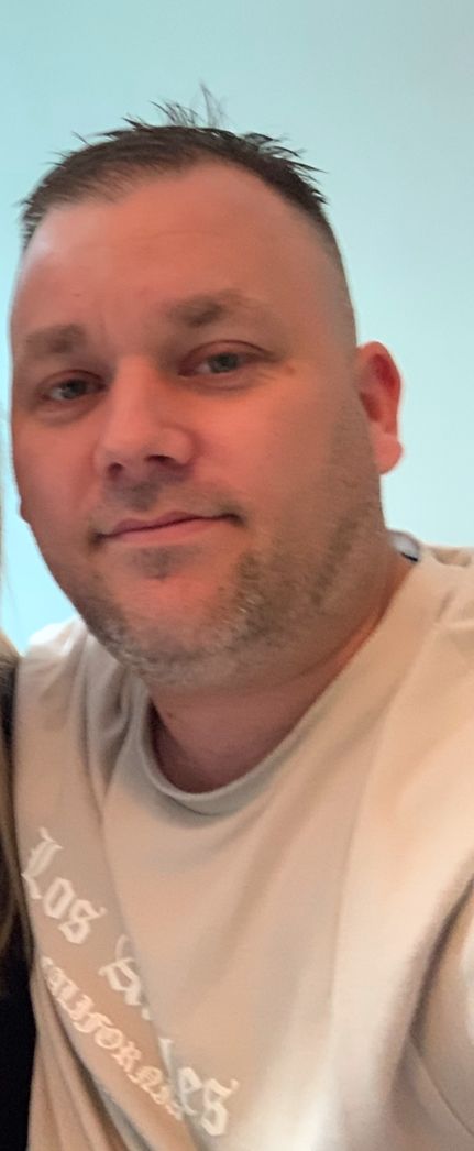 A man with short hair wearing a beige t-shirt