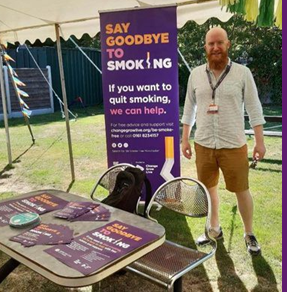 A man stood next to a roller banner about Be Smoke Free