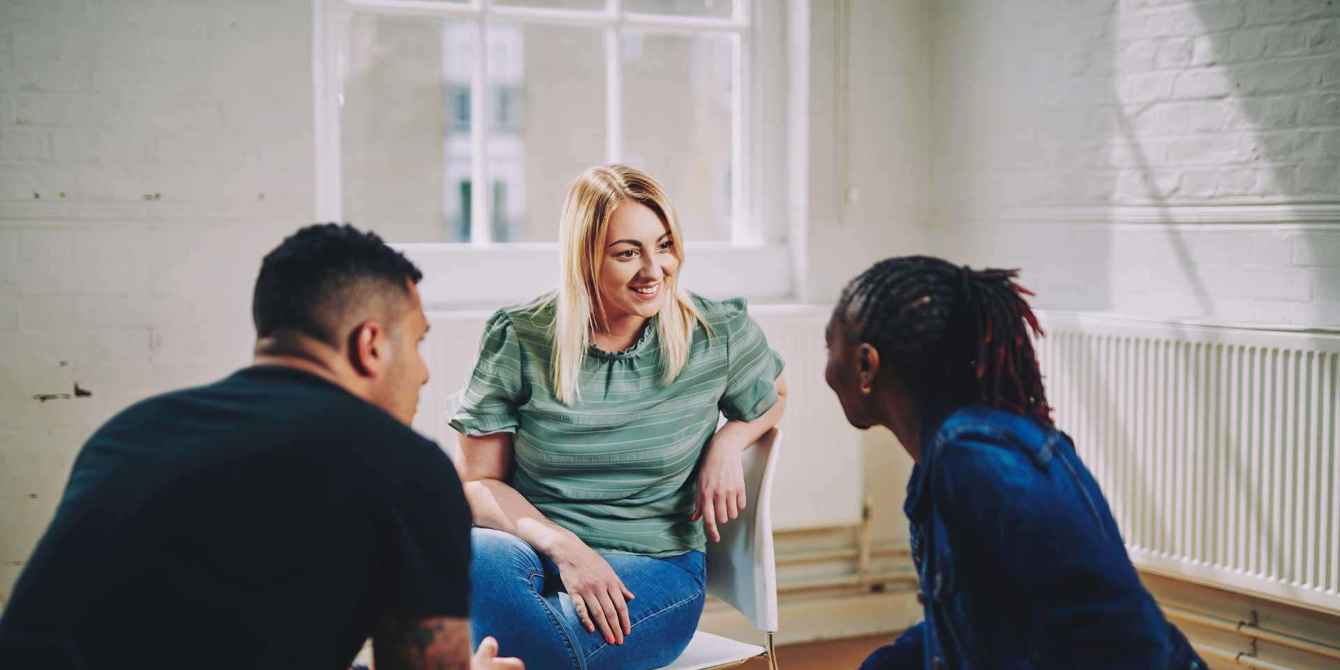 A woman and two men are sitting having a conversation