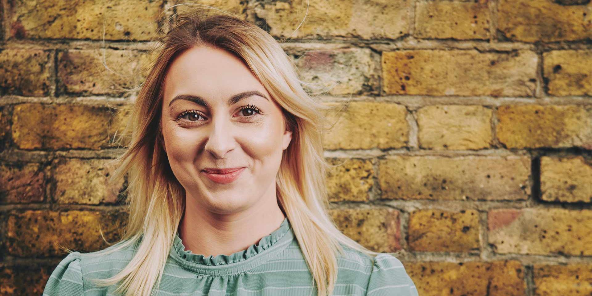 woman standing in front of a wall smiling