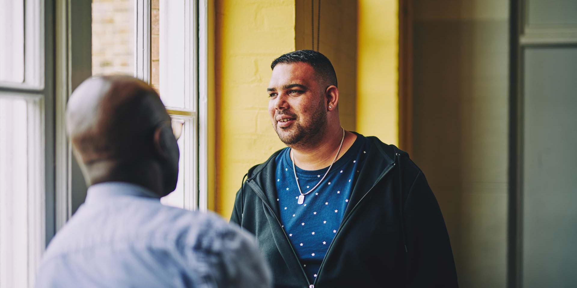 man having a conversation with another man and looking off into the distance