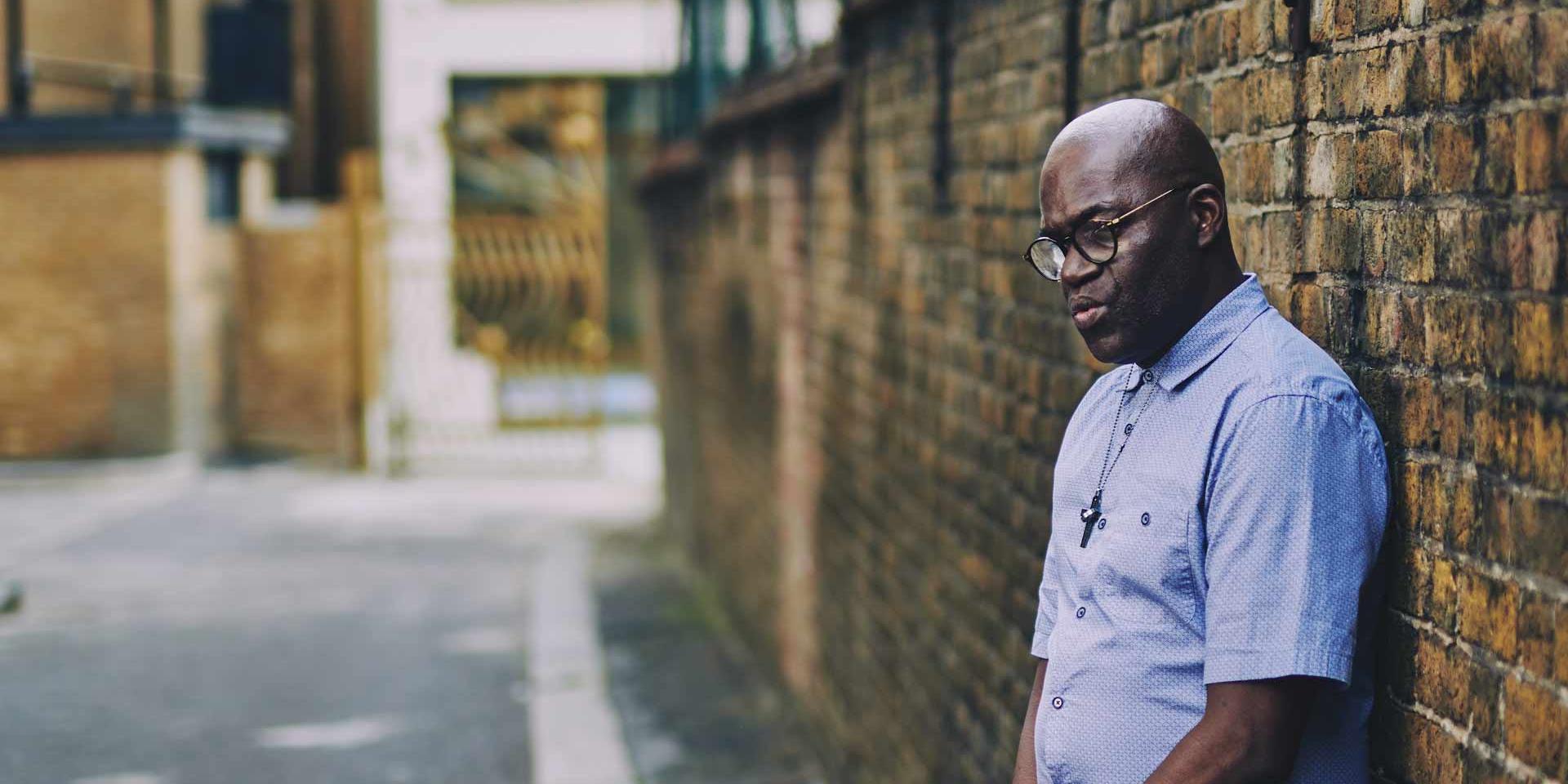 man looking down standing up against a wall