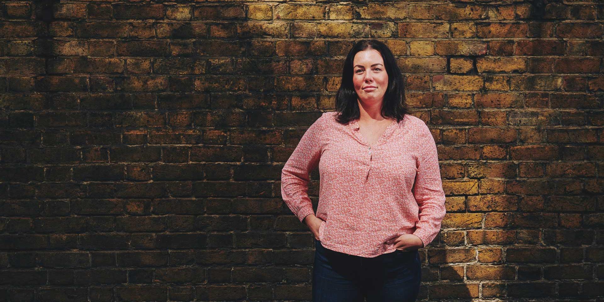 A woman stood in front of a brick wall