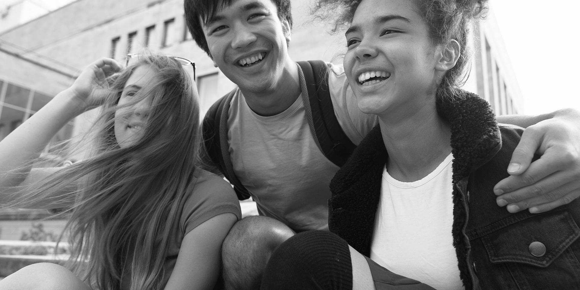 Three young people smiling and hugging