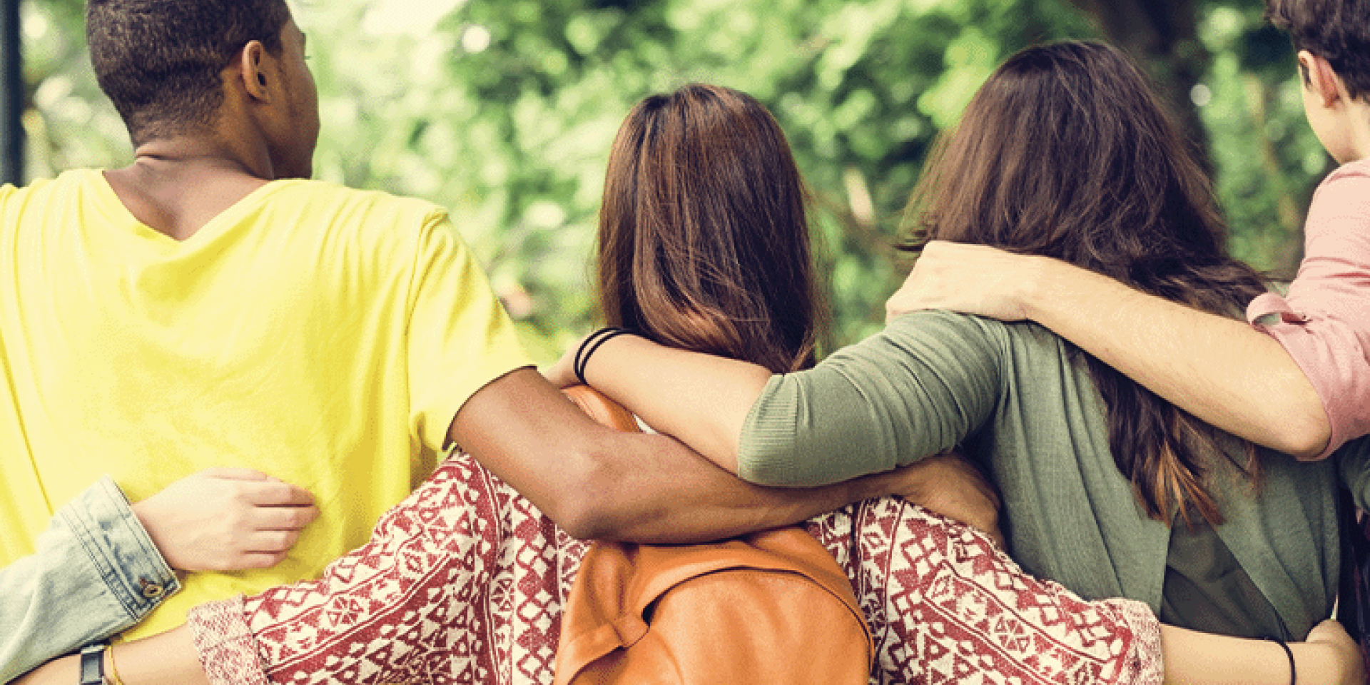 Five young people with their backs to the camera and arms around each other