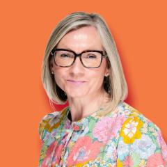 Vicki has a blonde bob and is wearing a colourful floral shirt and glasses