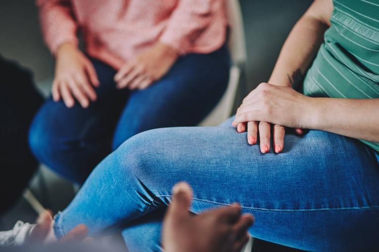 A woman has her hands folded on her lap