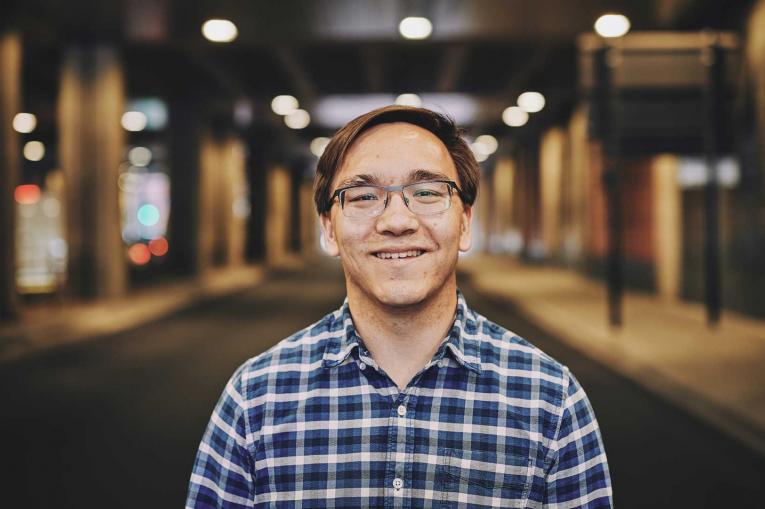 man smiling standing under a bridge