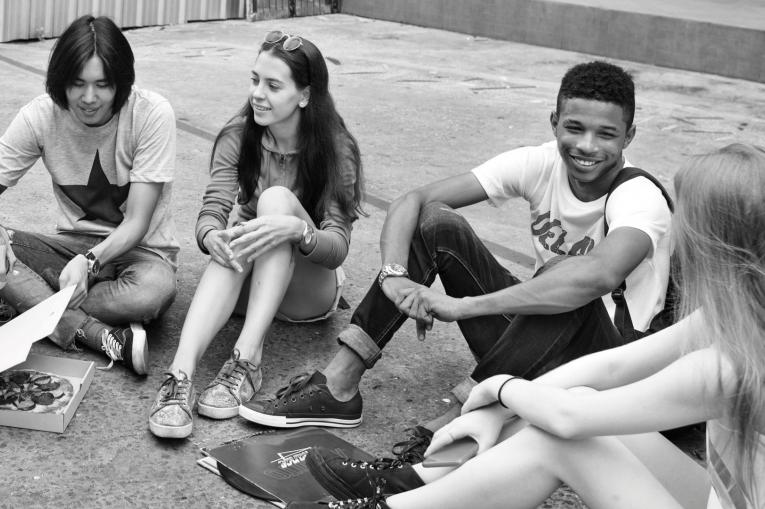 group of teenagers sitting around eating and talking