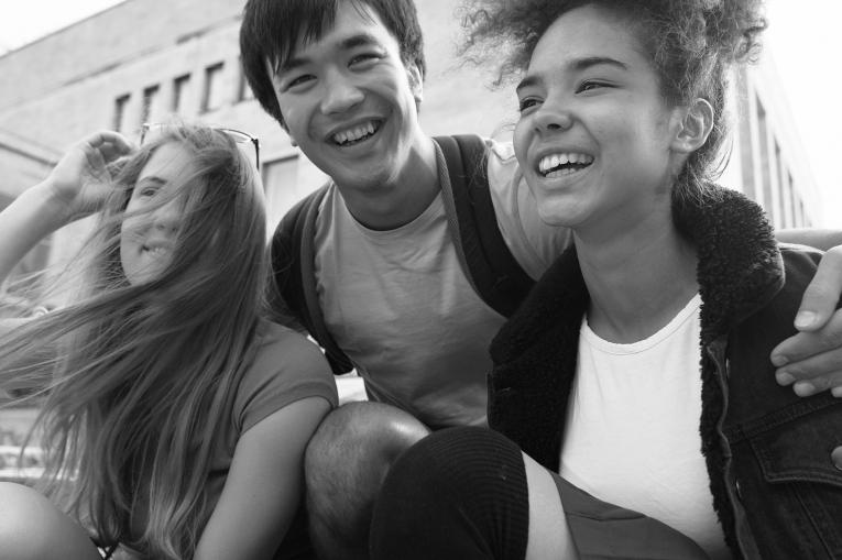 Three young people smiling and hugging