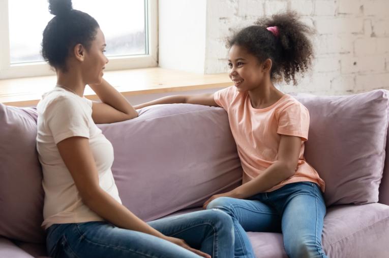 A woman and a child chatting while sat on a sofa