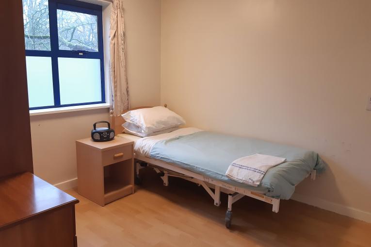 Bedroom - a single bed with blue sheets, a window and plain white walls