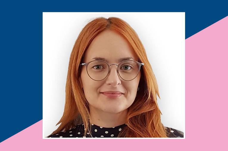 A photo of Loren, she has red hair and glasses. The photo sits on a background of pink and blue, split diagonally.