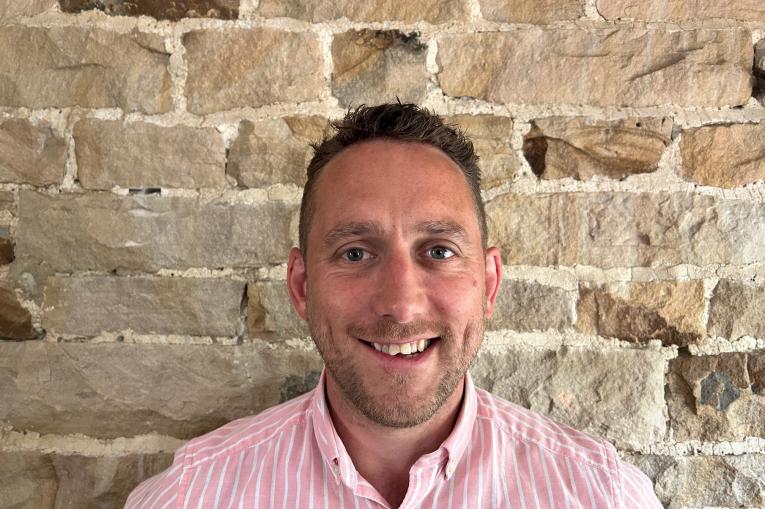 Image of a man in a pink and white striped shirt smiling