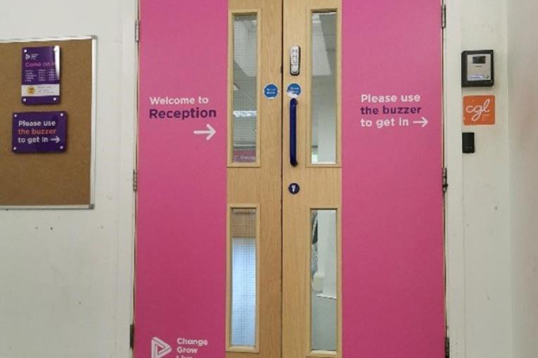 Double doors with pink banners either side letting you know how to enter