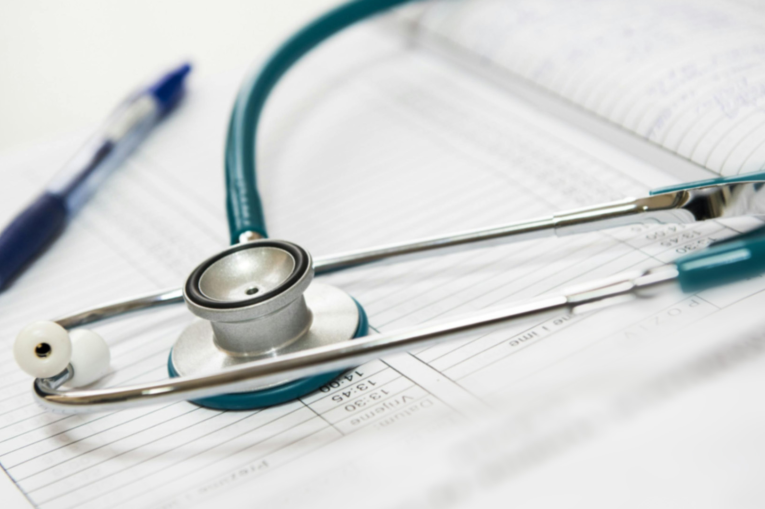 A stethoscope on a notebook next to a pen