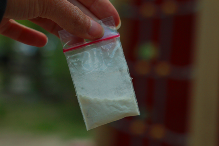 A hand holding a bag of Ketamine powder