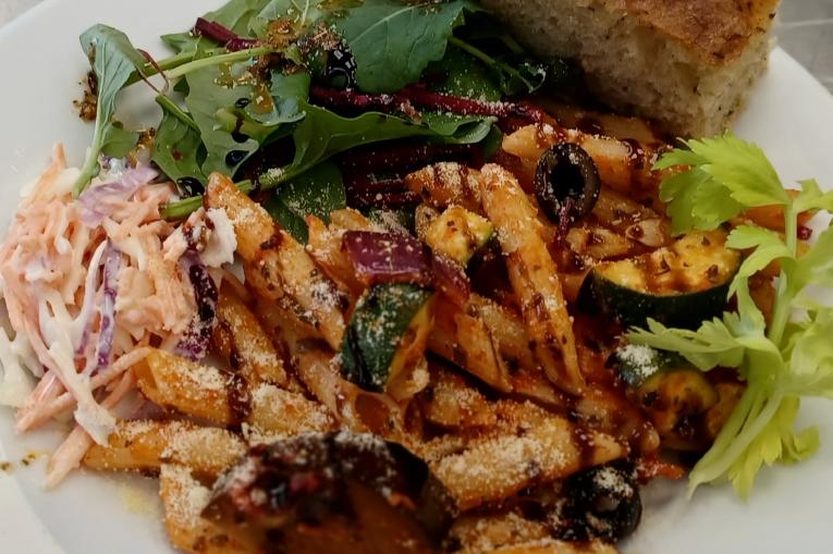 Pasta in sauce with bread and salad