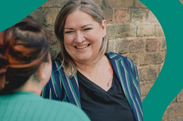 A staff member chats and smiles outside a service building