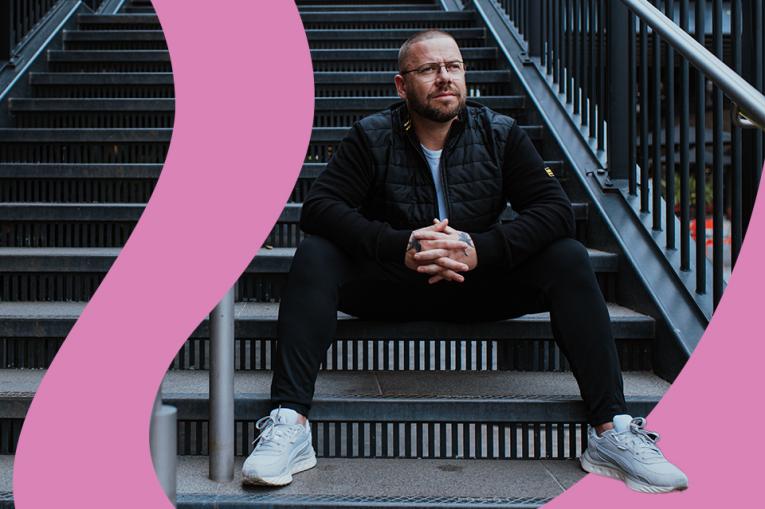 A person sitting on some stairs outside looking pensive
