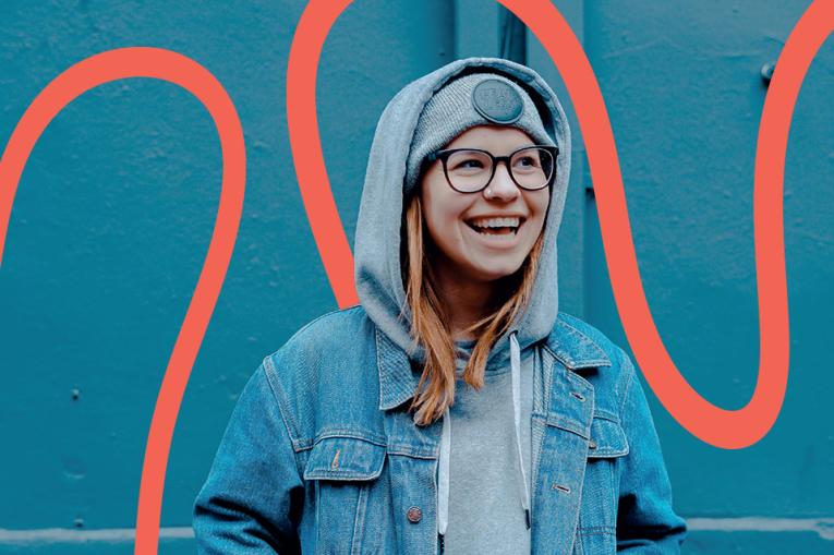 a young person smiling in front of a kingfisher blue background