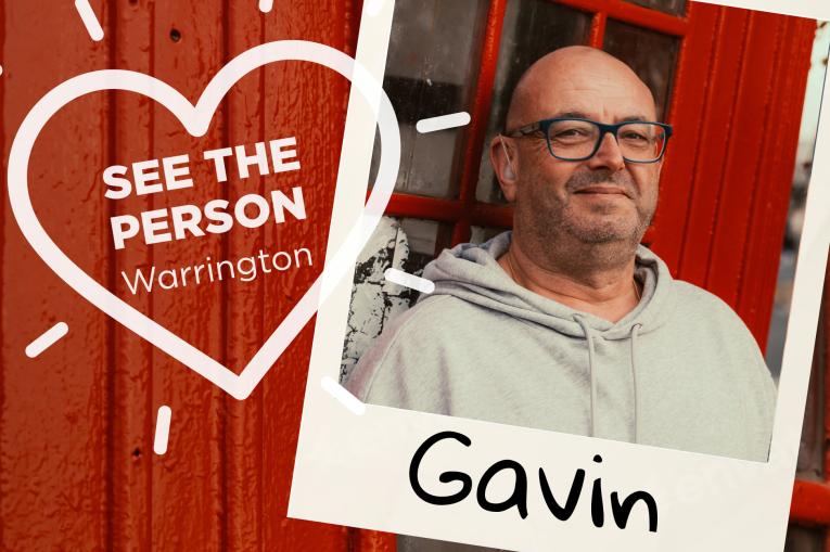 A colourful wall background with a heart stamp on the left with the words See The Person Warrington inside the heart. On the right is a polaroid photo with a blad man wearing glasses and a grey hoodie. The name Gavin is at the bottom of the polaroid.