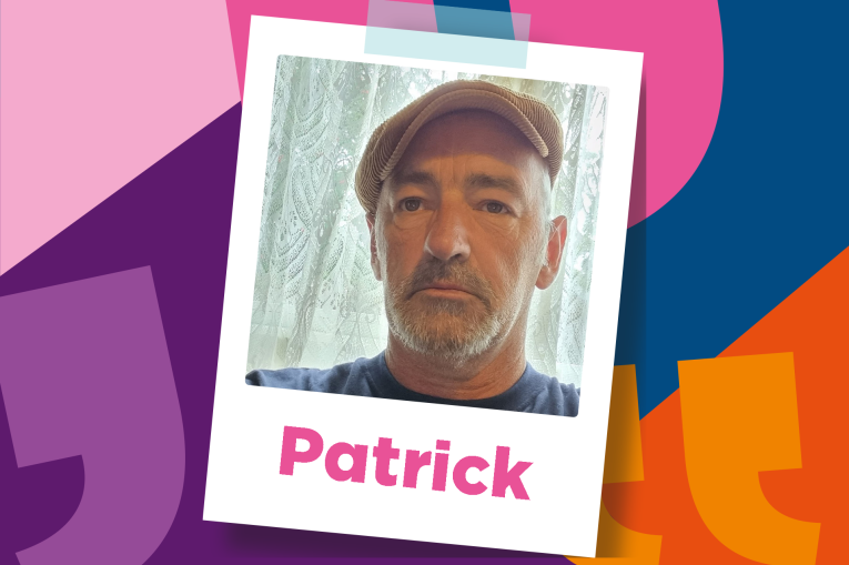 Patrick is wearing a brown flatcap and has a short beard and mustache