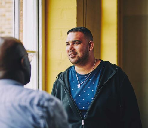 man having a conversation with another man and looking off into the distance