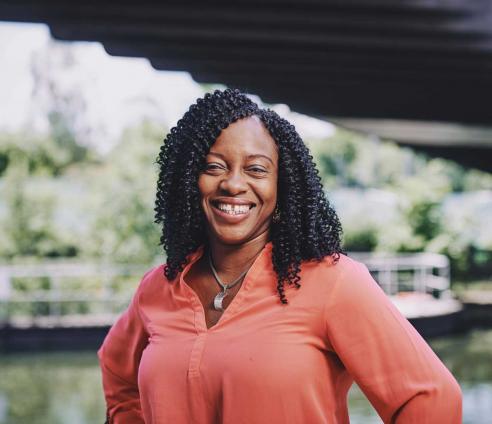 woman standing on a bridge smiling with water in the background