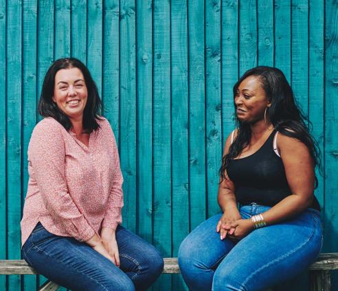 two women sitting on a bench talking and smiling
