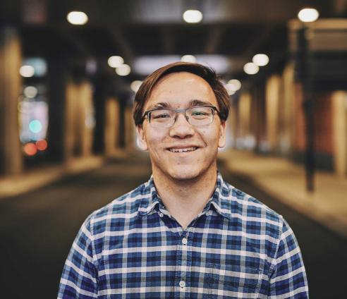 man smiling standing under a bridge