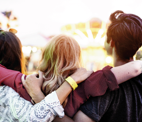 Trio of young people with backs to camera and arms around each other